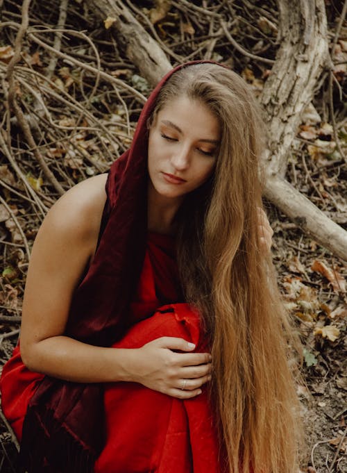 Woman in Red Scarf and Dress Sitting in Autumn Forest