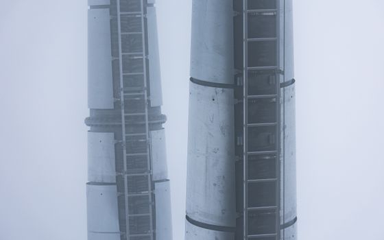 Tall industrial towers emerge through the mist, showcasing minimalist architecture.