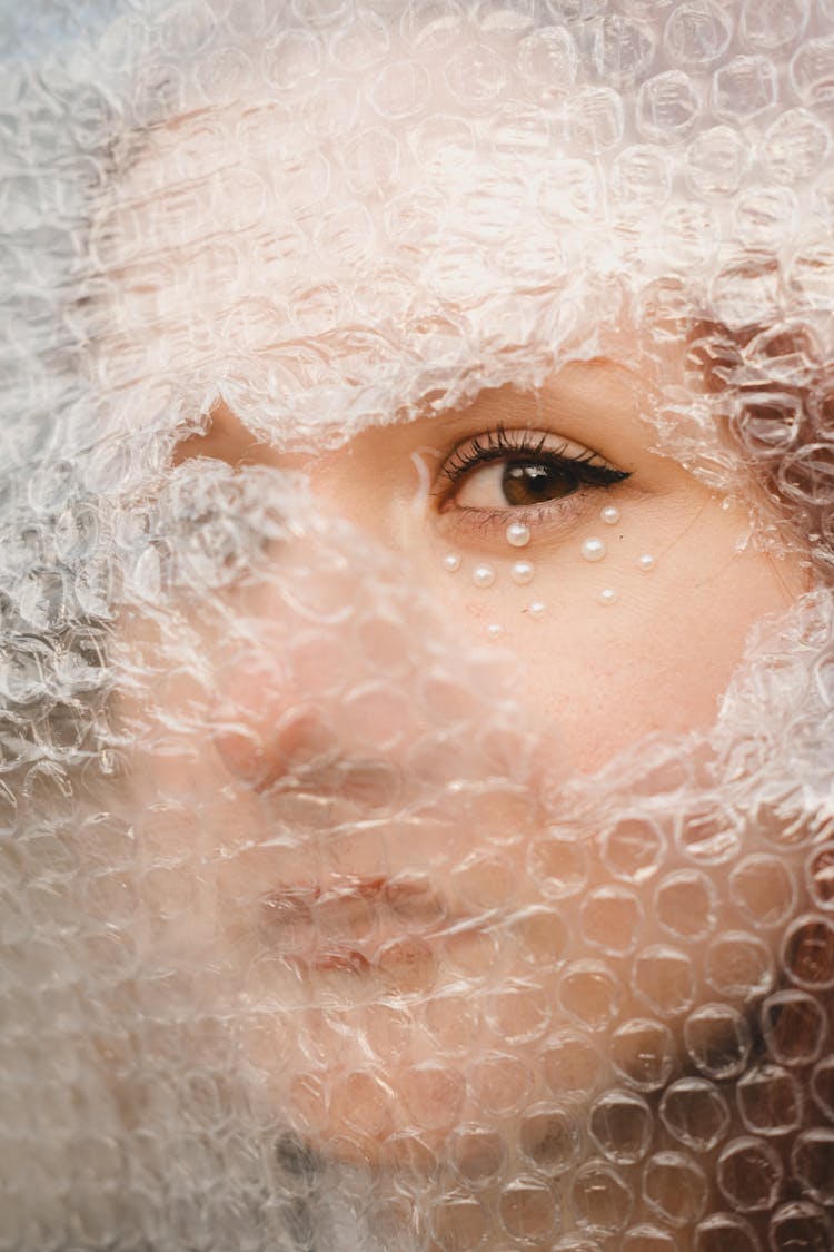 Close-up Of Woman Looking Through A Hole In A Bubble Wrap 