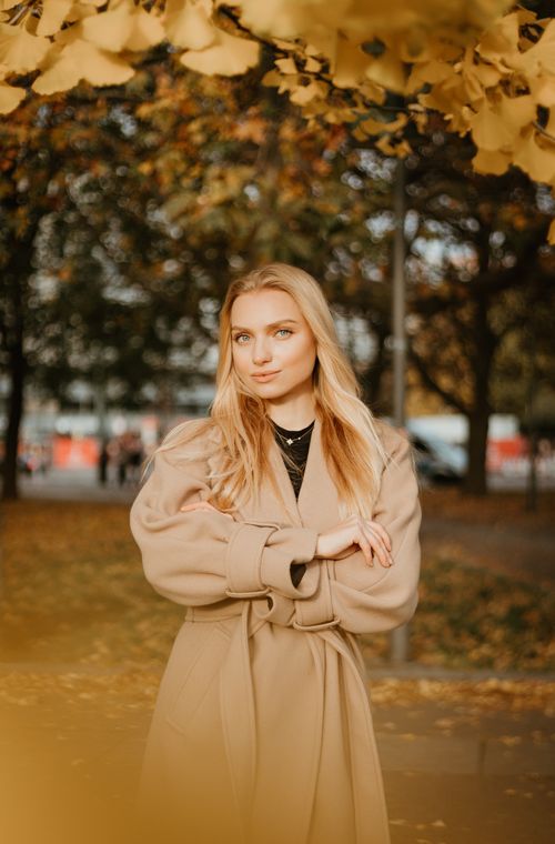 Free Stylish woman in autumn attire posing in a park surrounded by fall foliage. Stock Photo