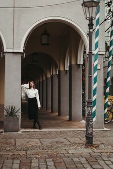 Elegant woman posing under a series of urban arches, capturing a sense of fashionable sophistication.