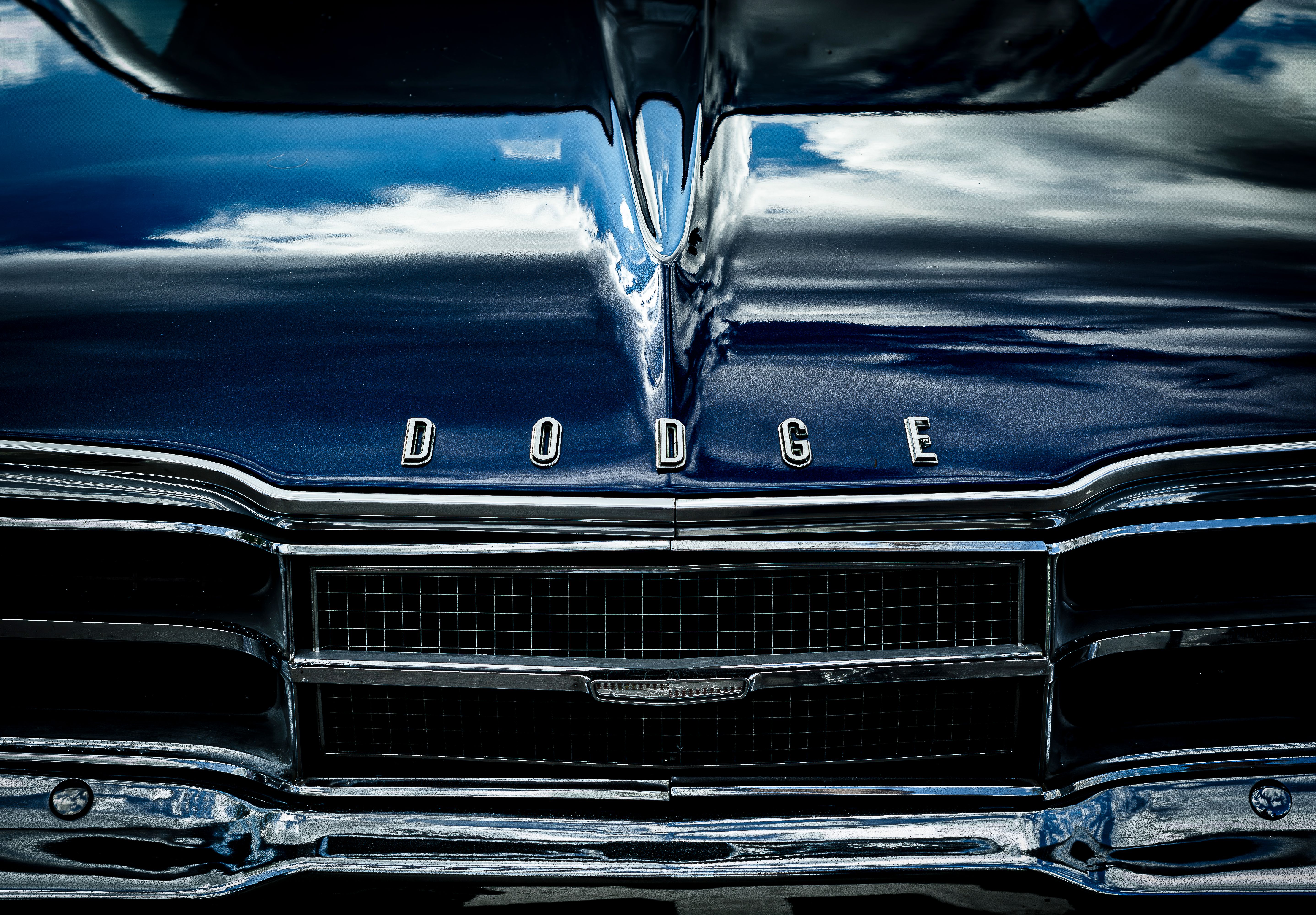 Close-up of the front view of a vintage Dodge car in metallic blue with chrome details.