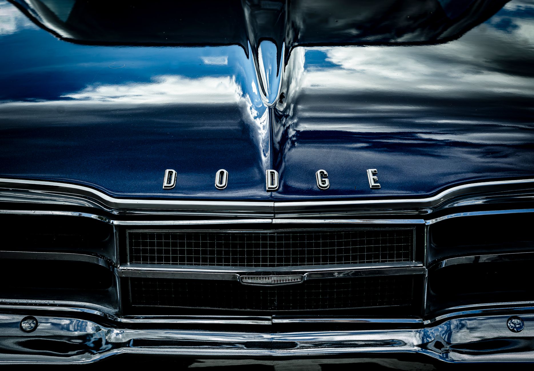 Close-up of the front view of a vintage Dodge car in metallic blue with chrome details.