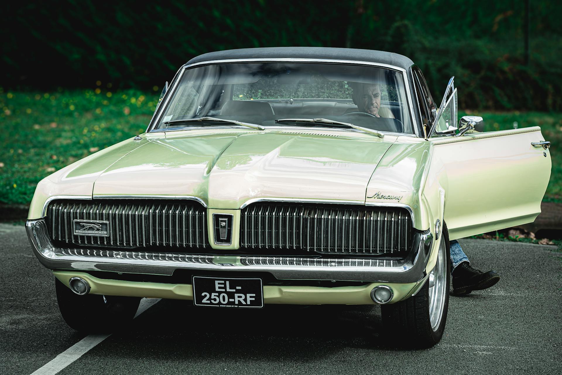 Classic Mercury Cougar with open door and driver outdoors.