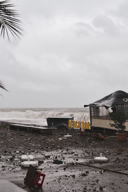Photo by Artem Makarov A coastal beach bar damaged by a recent storm with high waves, debris, and cloudy skies.