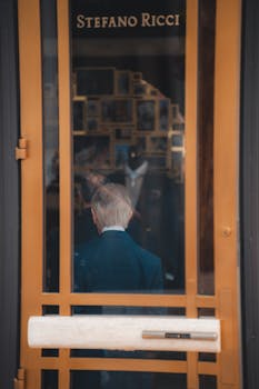 A sophisticated entrance with golden door frames and reflections of a stylish interior, seen through glass.