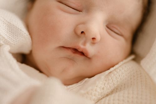 Free A serene close-up portrait of a newborn baby peacefully sleeping, wrapped in a soft blanket. Stock Photo
