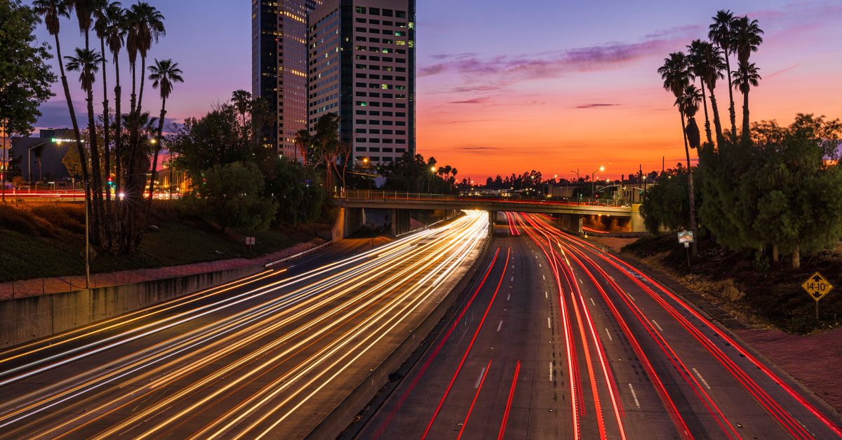 Vibrant sunset view of Burbank highway, palm trees, and light trails creating a dynamic urban scene.