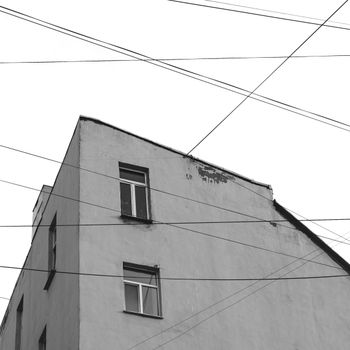 Black and white photo of a building facade with intersecting power lines in urban Saint Petersburg.