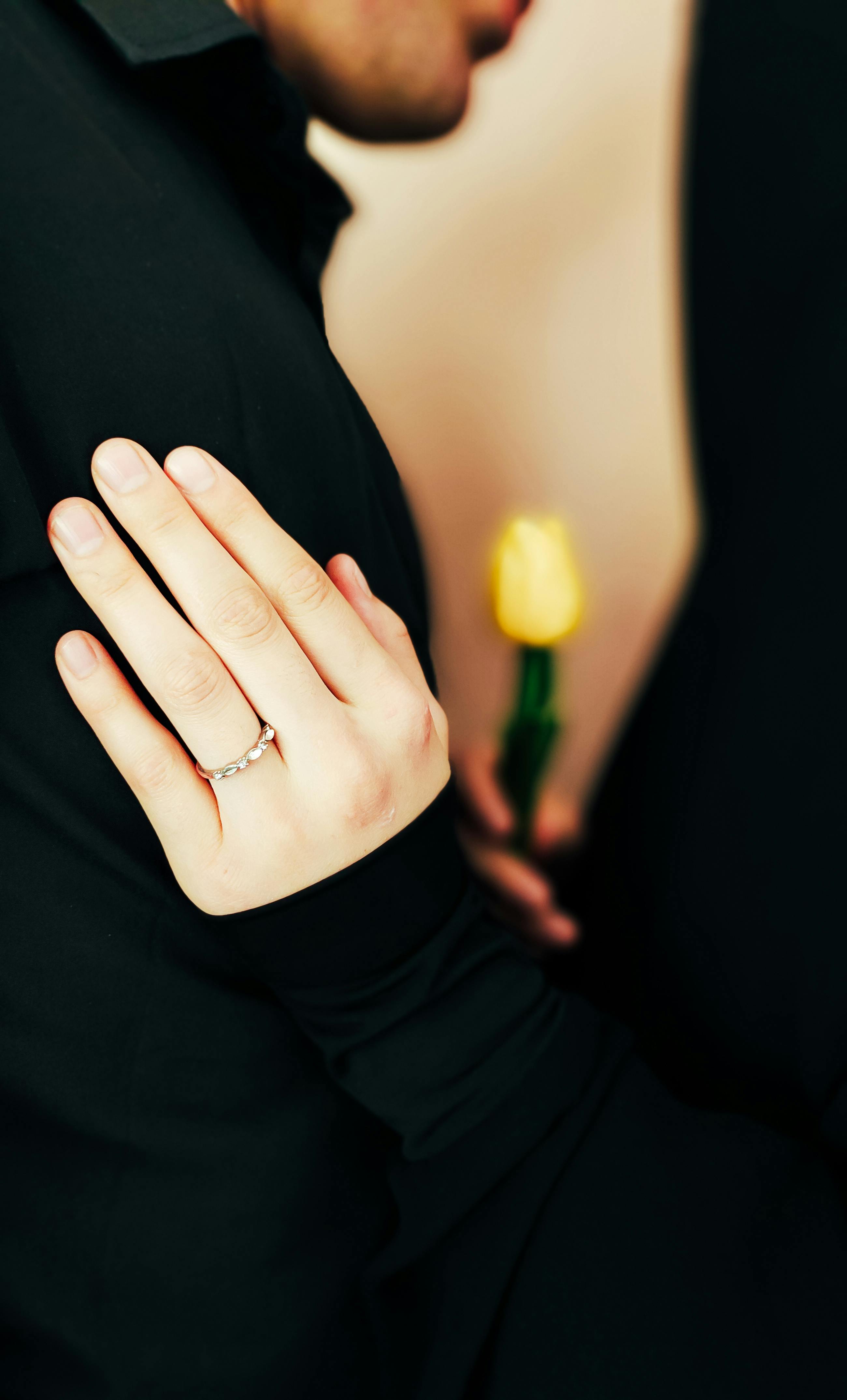 Premium Photo | A woman's hand with a ring on her finger is surrounded by  flowers.