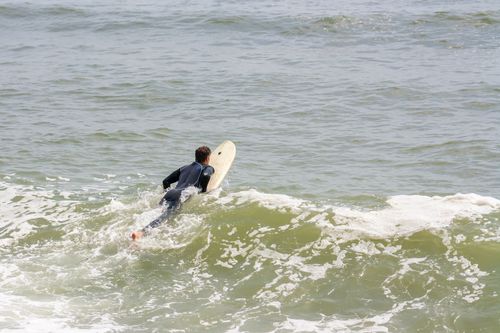 Free A surfer in a wetsuit paddling on a surfboard in the ocean waves near Lima, Peru. Stock Photo