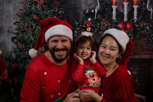 Happy Family in Red Pajamas and Santa Hats Among Christmas Ornaments