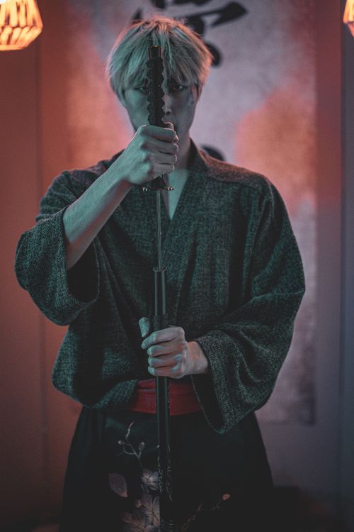 Free Portrait of a samurai in a kimono holding a katana, captured in dramatic indoor lighting. Stock Photo