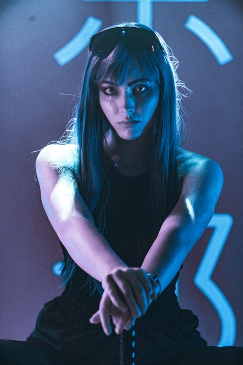 Woman Sitting with Her Hands resting on the Hilt of a Sword in Neon Light