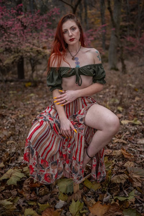 Redhead Woman in Skirt Sitting in Forest