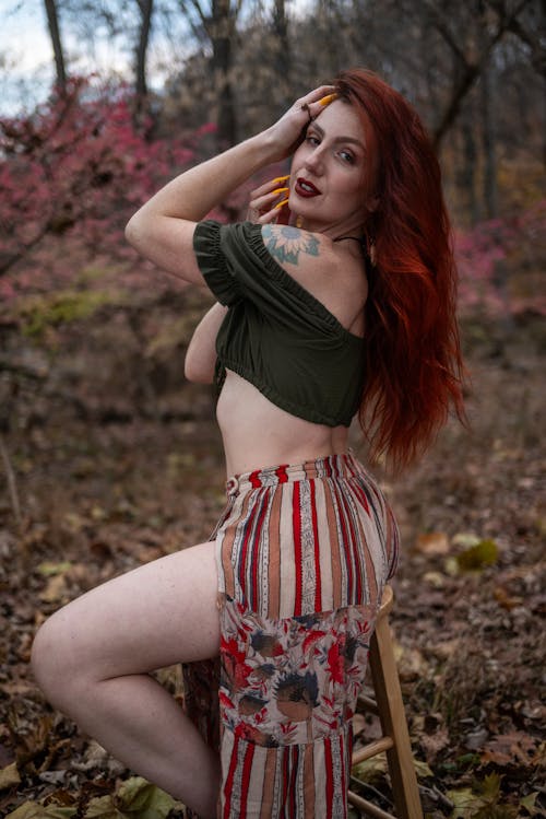 Woman in a Green Crop Top and a Slit Skirt Posing Sitting on a Stool in the Forest