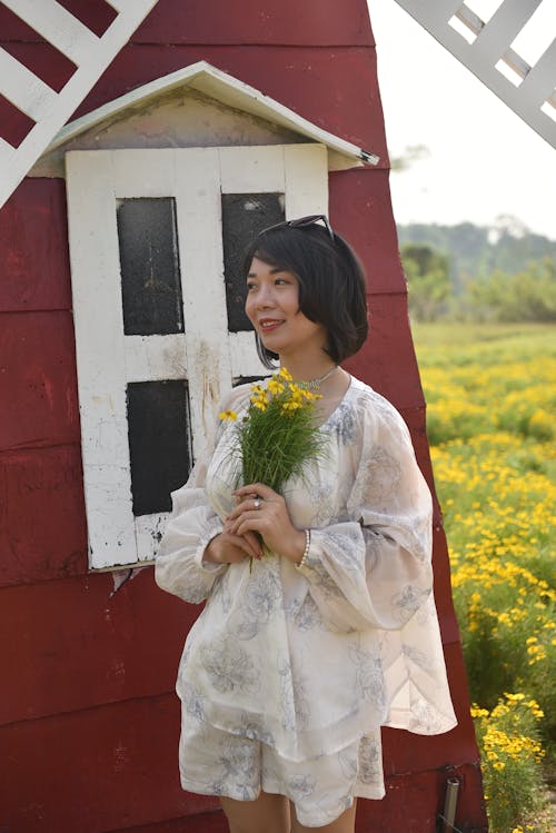 Woman with a Bouquet of Flowers Standing in front of a Windmill 