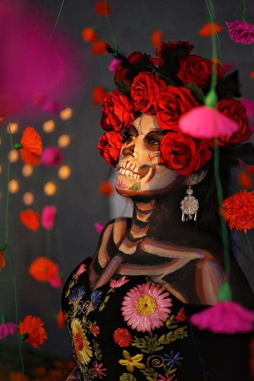 Photo of a Woman Dressed as a Catrina Standing among Flowers