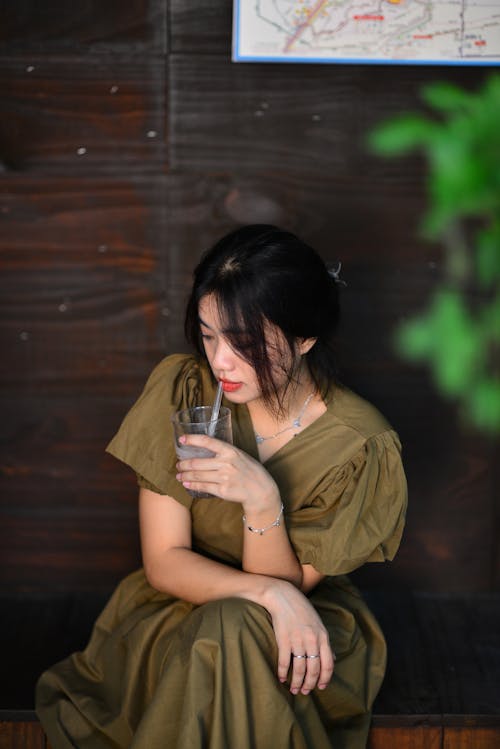 Brunette Woman in Dress Sitting and Drinking Water