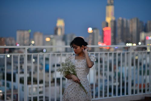 Brunette Woman in Floral Dress Posing on Terrace in City