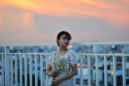 Pretty Woman in Floral Dress Posing on Terrace at Dusk