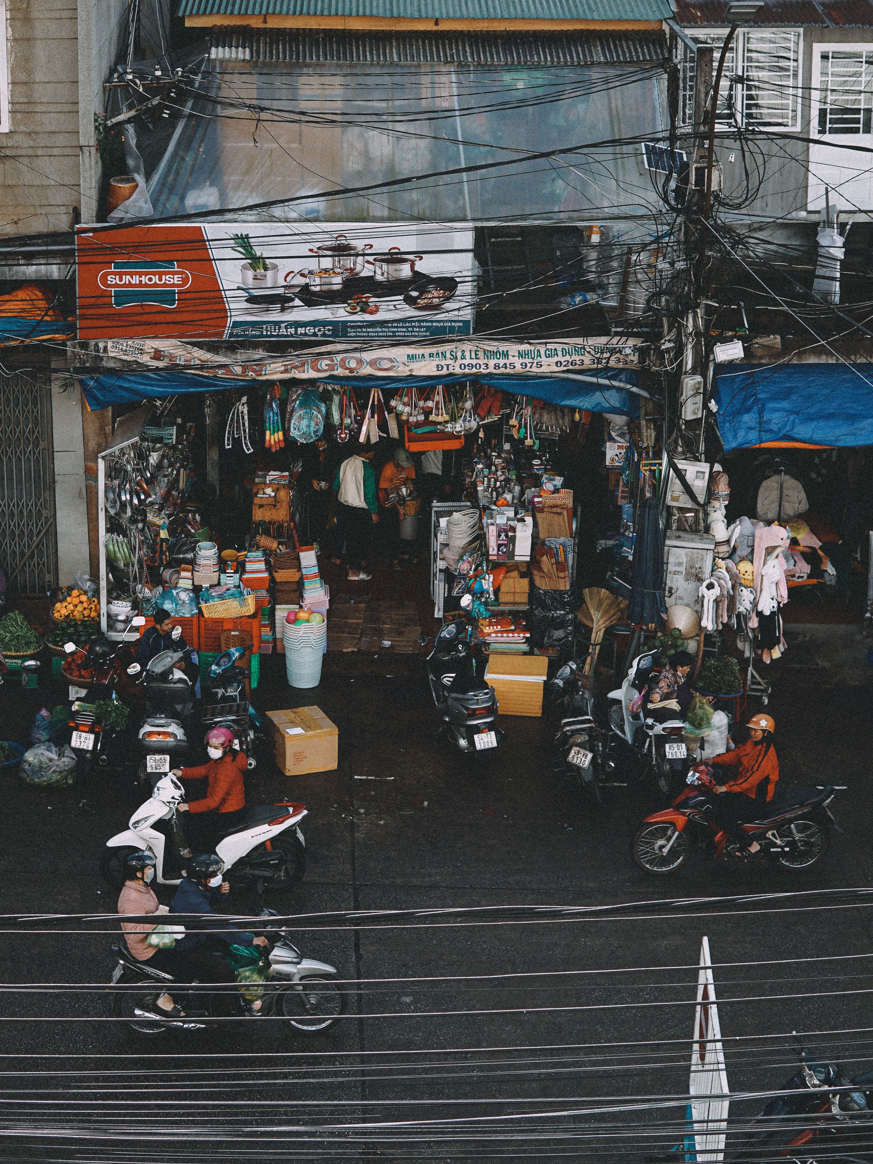 Vibrant street scene with scooters and a busy market storefront in Dalat, Vietnam.