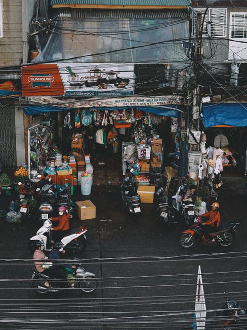 Vibrant street scene with scooters and a busy market storefront in Dalat, Vietnam.