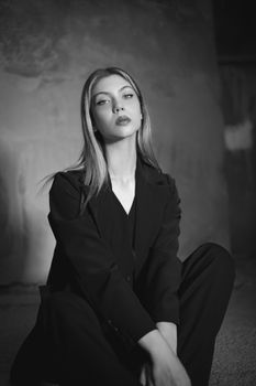 Black and white portrait of a woman in a blazer, exuding elegance and fashion in a seated pose.