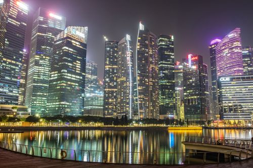 Free Illuminated skyscrapers reflecting on Marina Bay in Singapore at night, showcasing modern urban architecture. Stock Photo