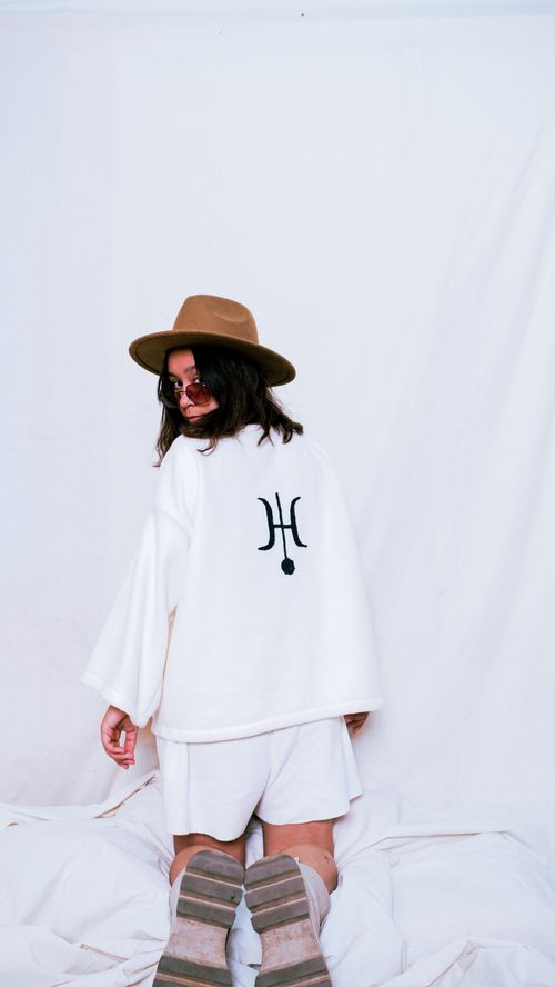 Free Stylish woman in white attire with a hat and sunglasses poses against a white background. Stock Photo
