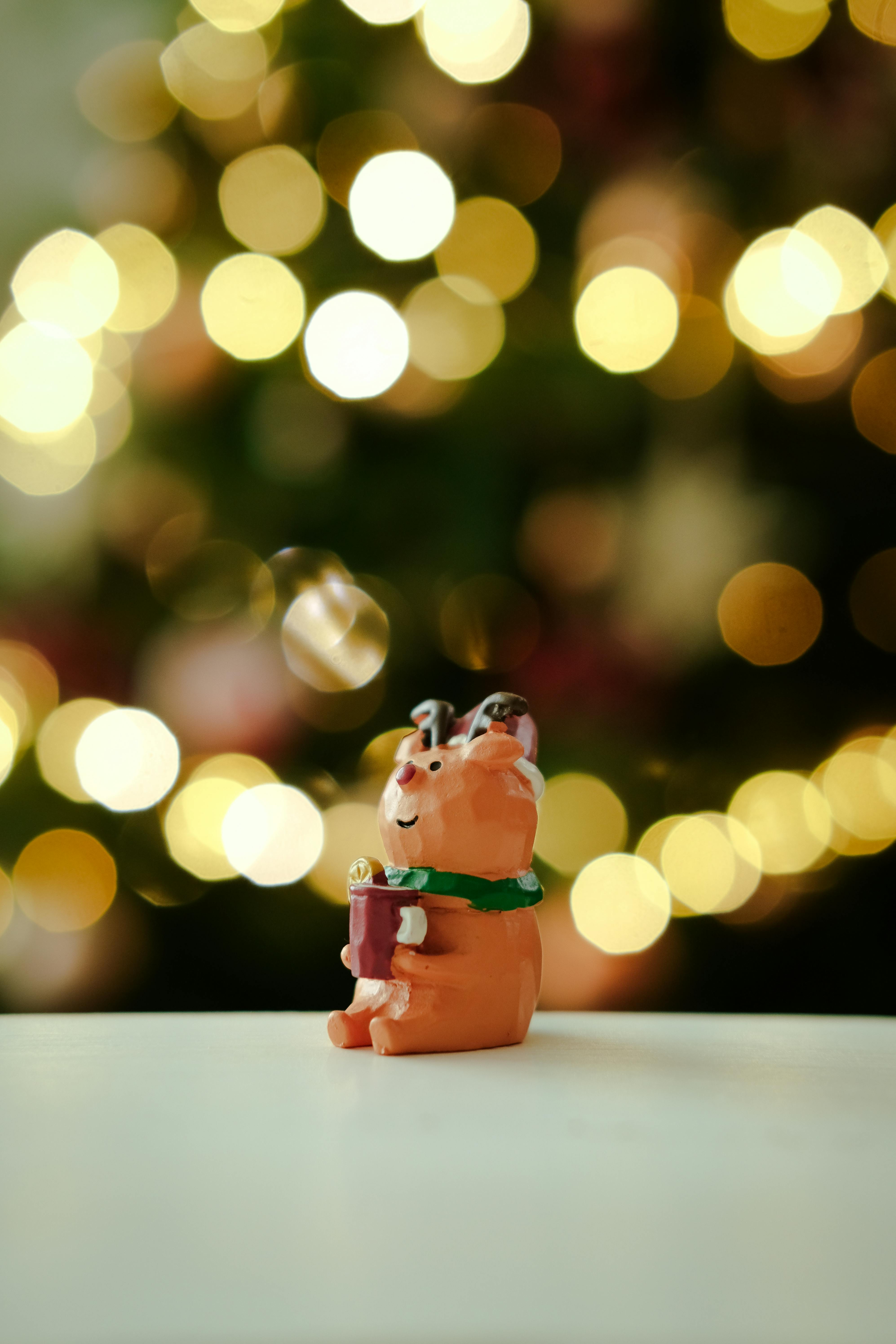 A cute reindeer figurine with festive bokeh lights in the background, capturing the holiday spirit.