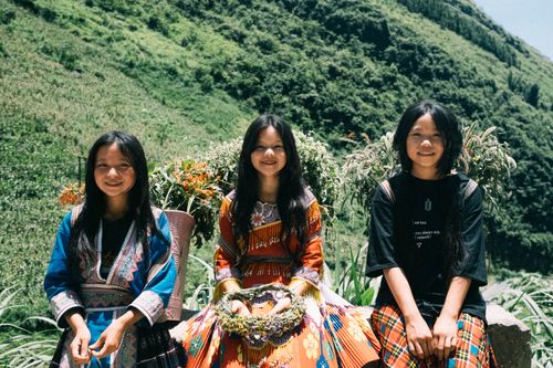 Free Three young girls smiling outdoors in traditional clothing, enjoying a sunny day in the countryside. Stock Photo