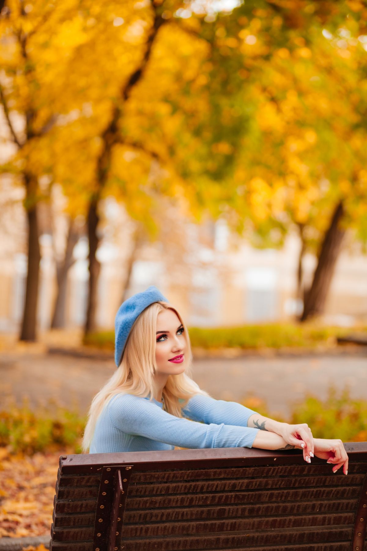 A blonde woman sitting on a bench in the park · Free Stock Photo