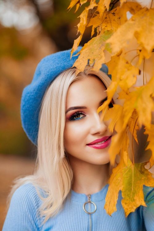 Free Smiling woman in blue beret surrounded by vibrant autumn leaves in Schlosshof, Austria. Stock Photo