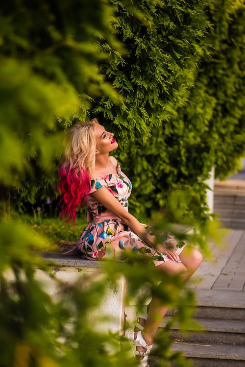Free Blond woman with vibrant outfit enjoying leisure time outdoors in a park setting. Stock Photo