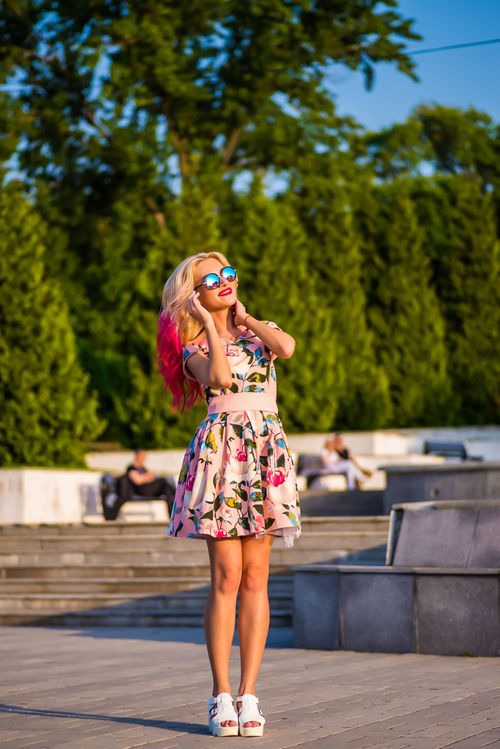 Free Stylish woman in floral dress and sunglasses enjoying a sunny day in the park. Stock Photo