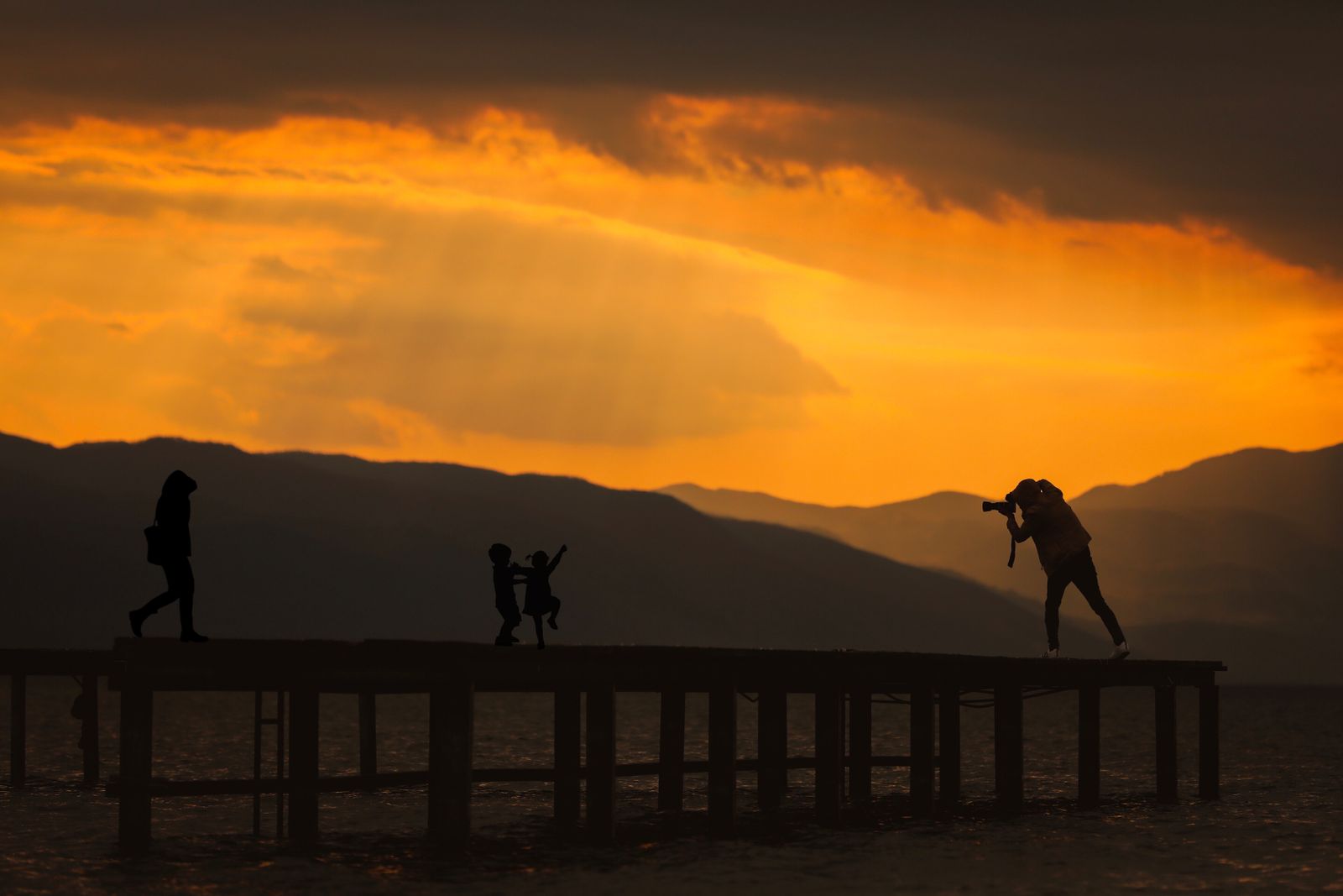 Silueta de una familia en un muelle al atardecer