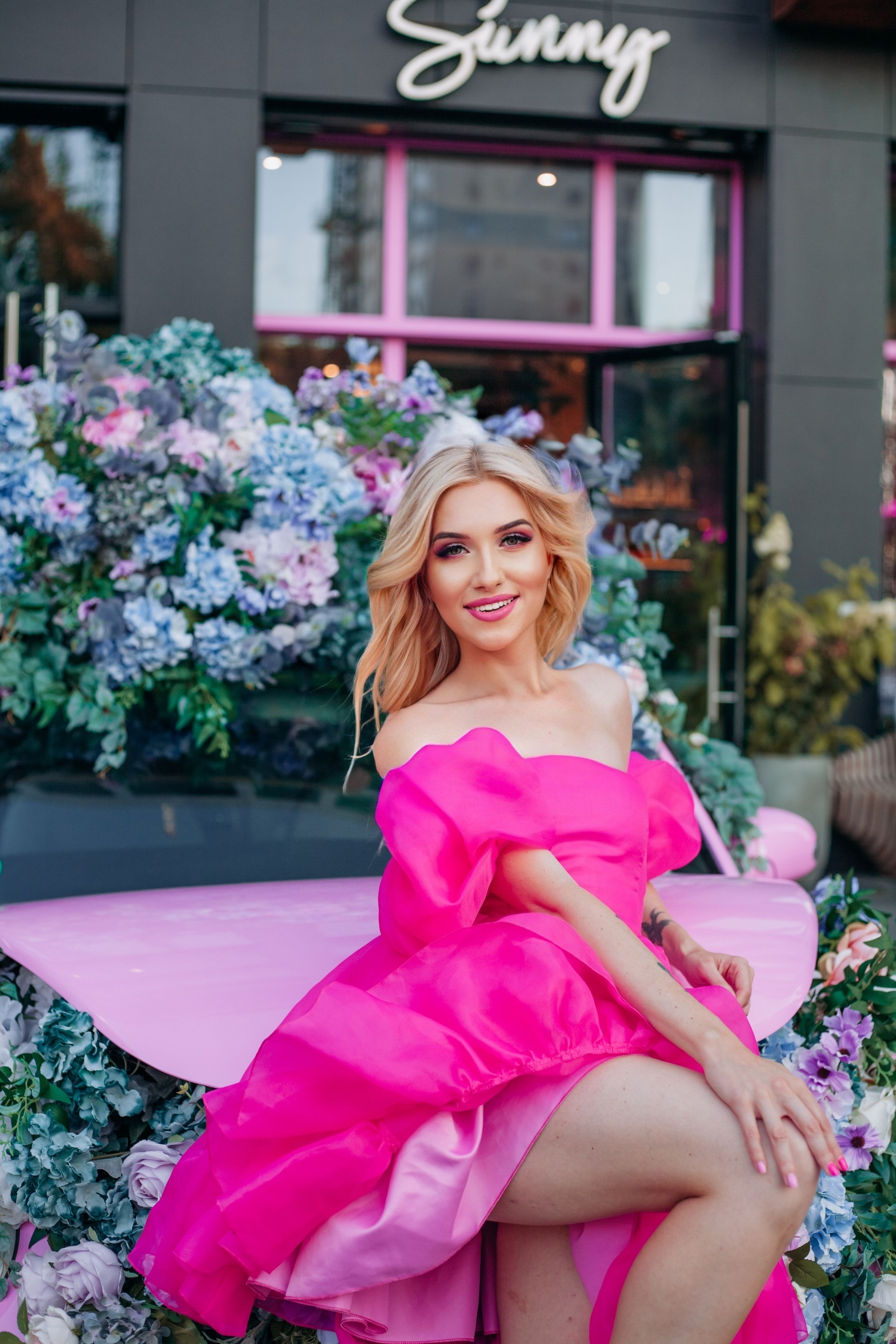 A blonde woman in a pink dress sitting on a pink car · Free Stock Photo