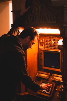 Man using a vintage ATM with illuminated keypad in Ankara, Türkiye.
