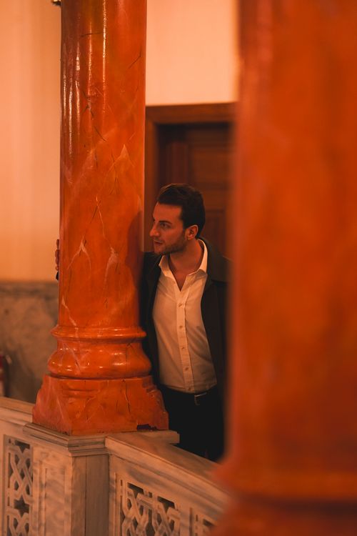 Free Man in white shirt poses by marble columns in Ankara, creating a sophisticated ambiance. Stock Photo