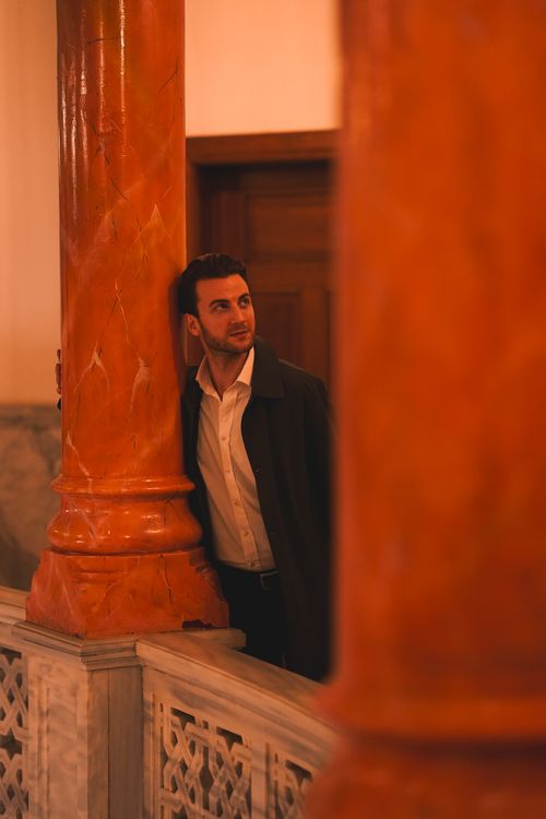 Free A stylish man poses elegantly by marble columns in a historic building in Ankara, Türkiye. Stock Photo
