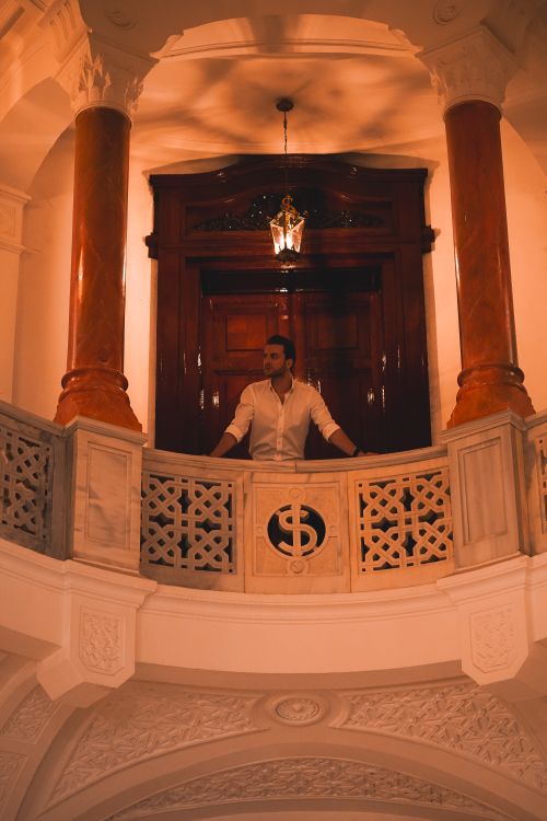 Free A man in a white shirt elegantly poses in a luxurious Ankara interior with tall columns. Stock Photo