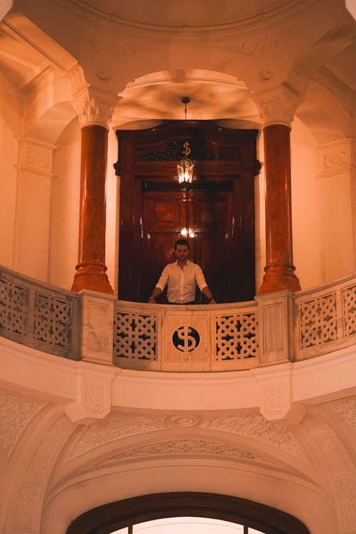 Free A stylish man in a white shirt stands on a classic balcony within an elegant interior in Ankara, Türkiye. Stock Photo