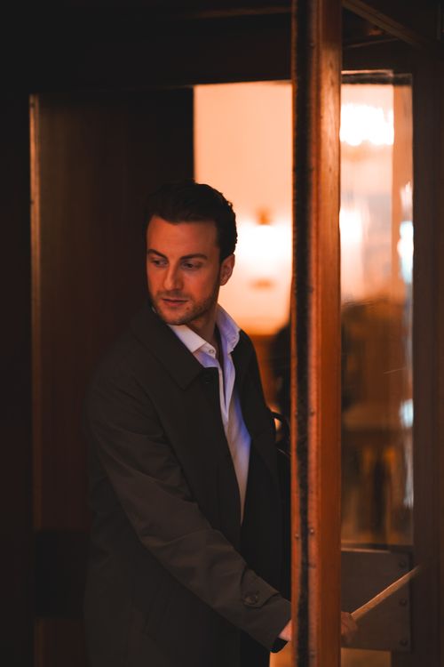 Free A man in a dark coat opening a door, captured in an elegant setting in Ankara, Türkiye. Stock Photo