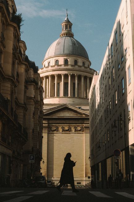 Silhouette of person walking in front of Paris's Panthéon under clear skies.