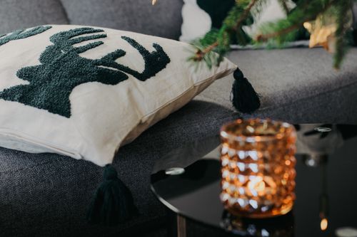 Free Warm living room scene with reindeer pillow and glowing candle. Stock Photo