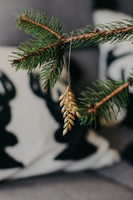 Close-up of a gold ornament hanging on a Christmas tree branch indoors.