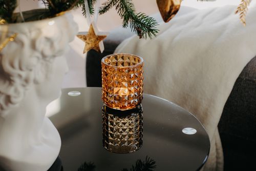 Free A geometric candle holder on a reflective coffee table with festive decor, evoking warmth and elegance. Stock Photo