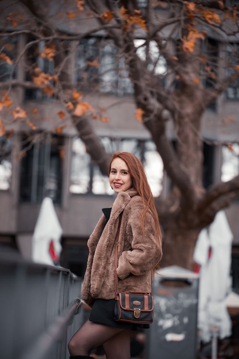 Woman in faux fur coat with bag on a city street