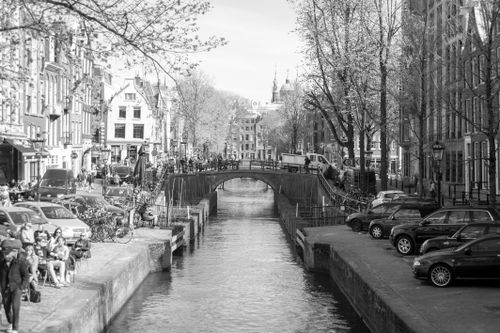 Free Black and white view of an Amsterdam canal with bridge and historic facades, ideal for urban tourism imagery. Stock Photo